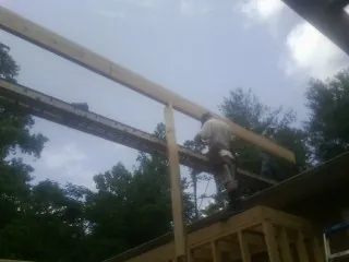 Carpenter setting a ridge beam over a new addition frame — Ice Dam Removal by Roofing Brothers in Lyons