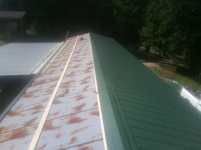 Old rusted panels beside newly installed green metal roofing — Wind Damage Roof Repair by Roofing Brothers in Lyons